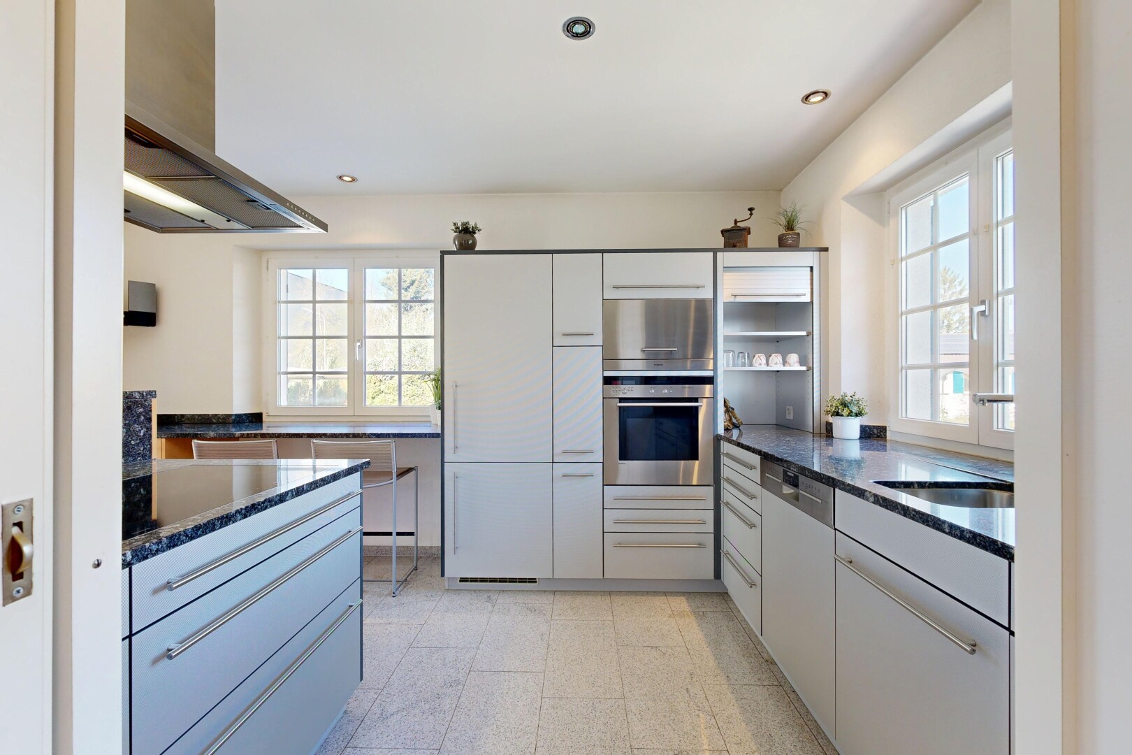 cuisine avec dark countertops, hotte, four, stone countertops, et plans de travail en pierre