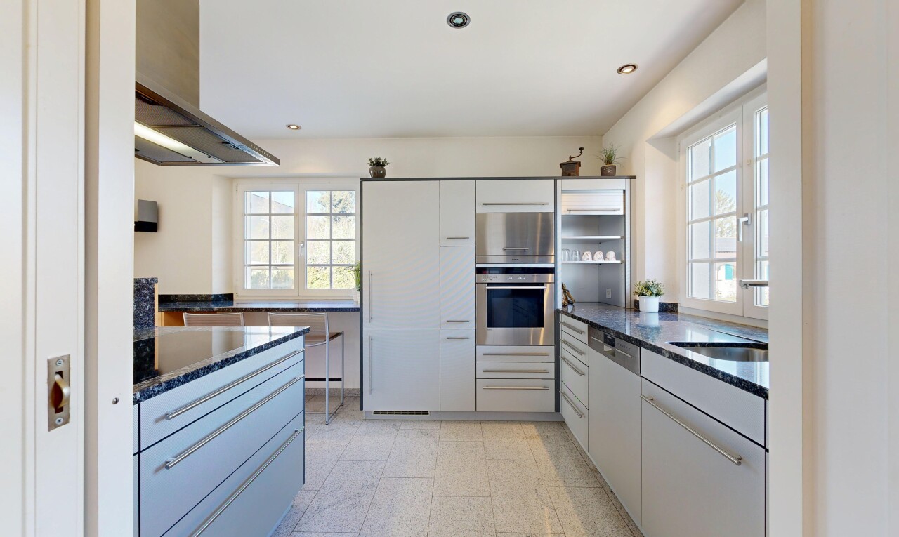 cuisine avec dark countertops, hotte, four, stone countertops, et plans de travail en pierre
