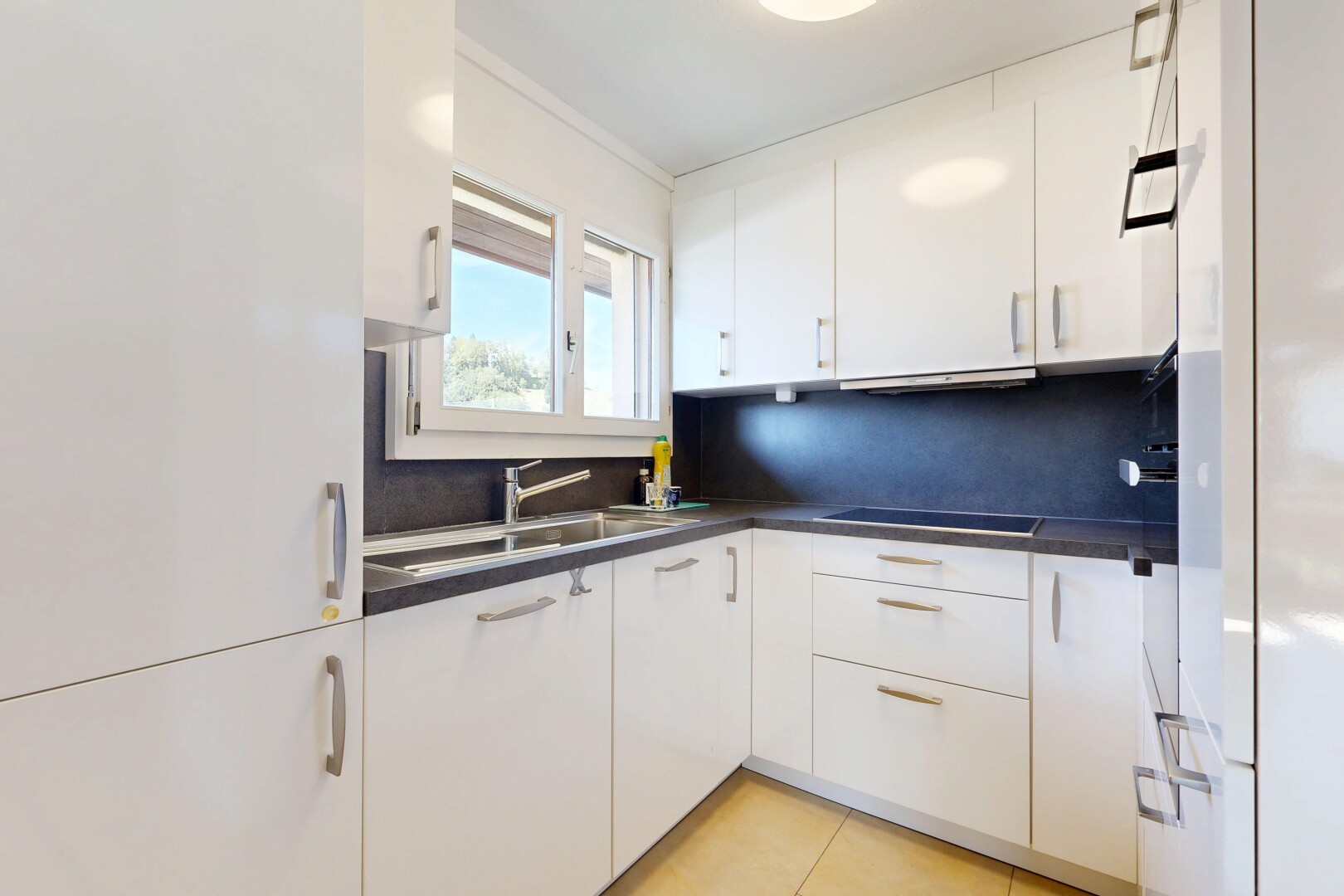 cuisine avec plans de travail, dark countertops, armoires blanches, white cabinets, et évier