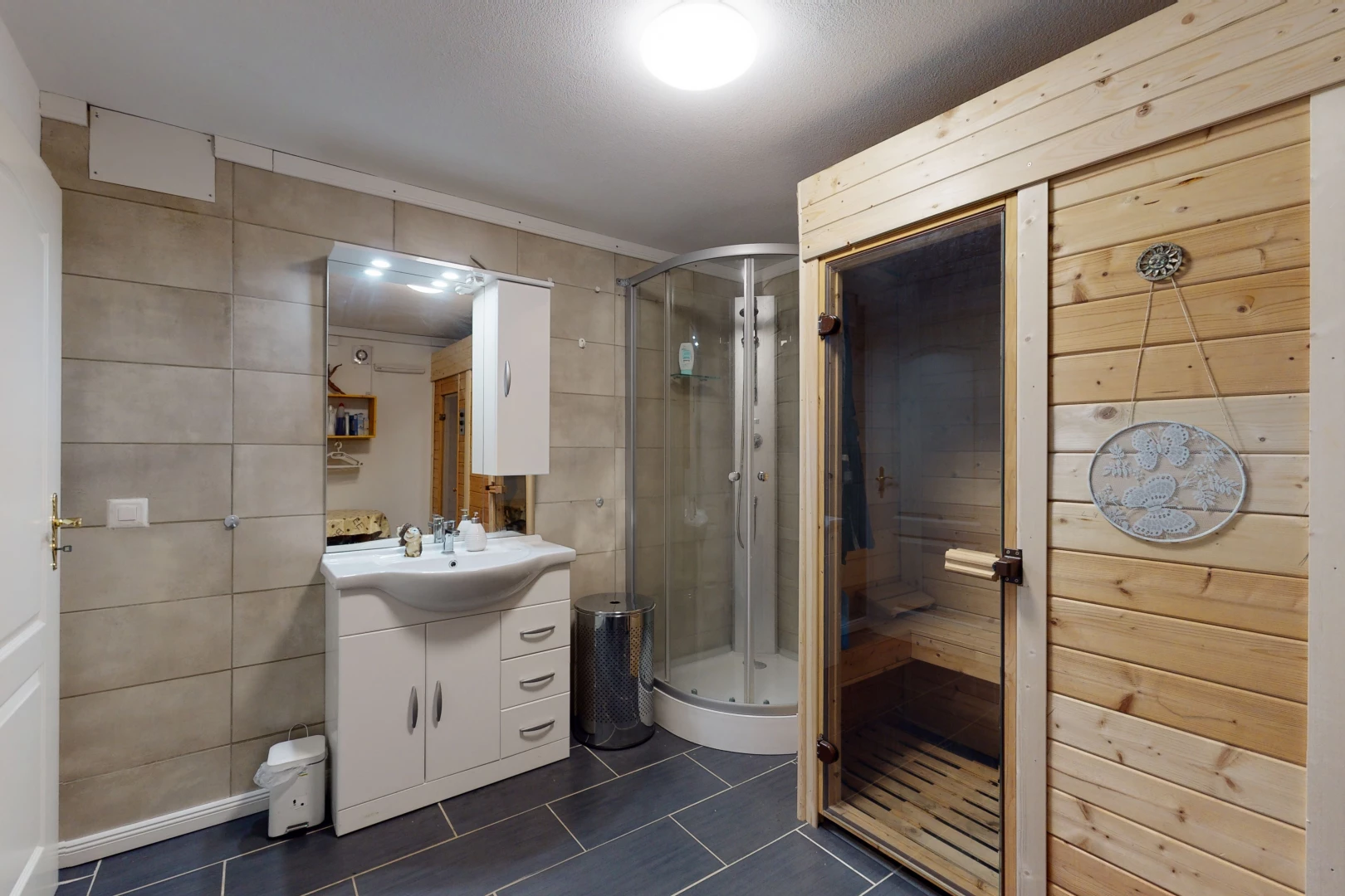 salle de bains avec carrelage, vasque, douche, porte de douche, meuble-lavabo, et miroir