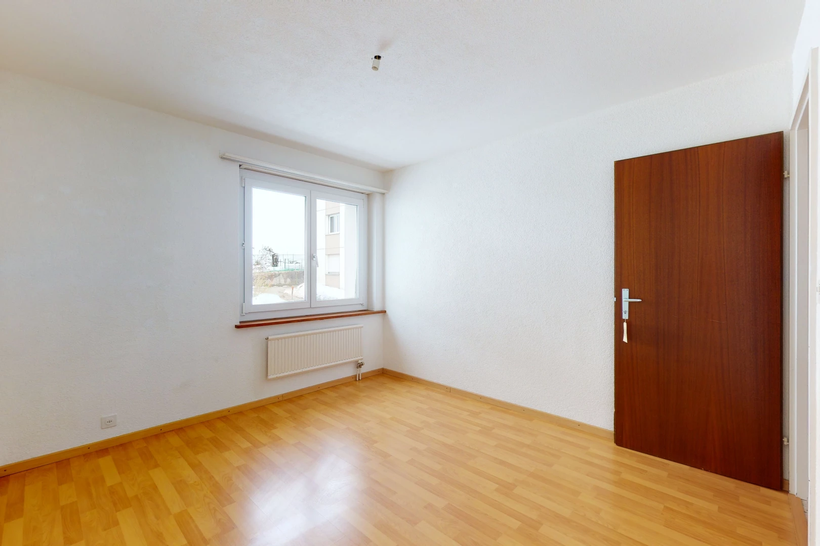 hardwood floored spare room featuring natural light and radiator