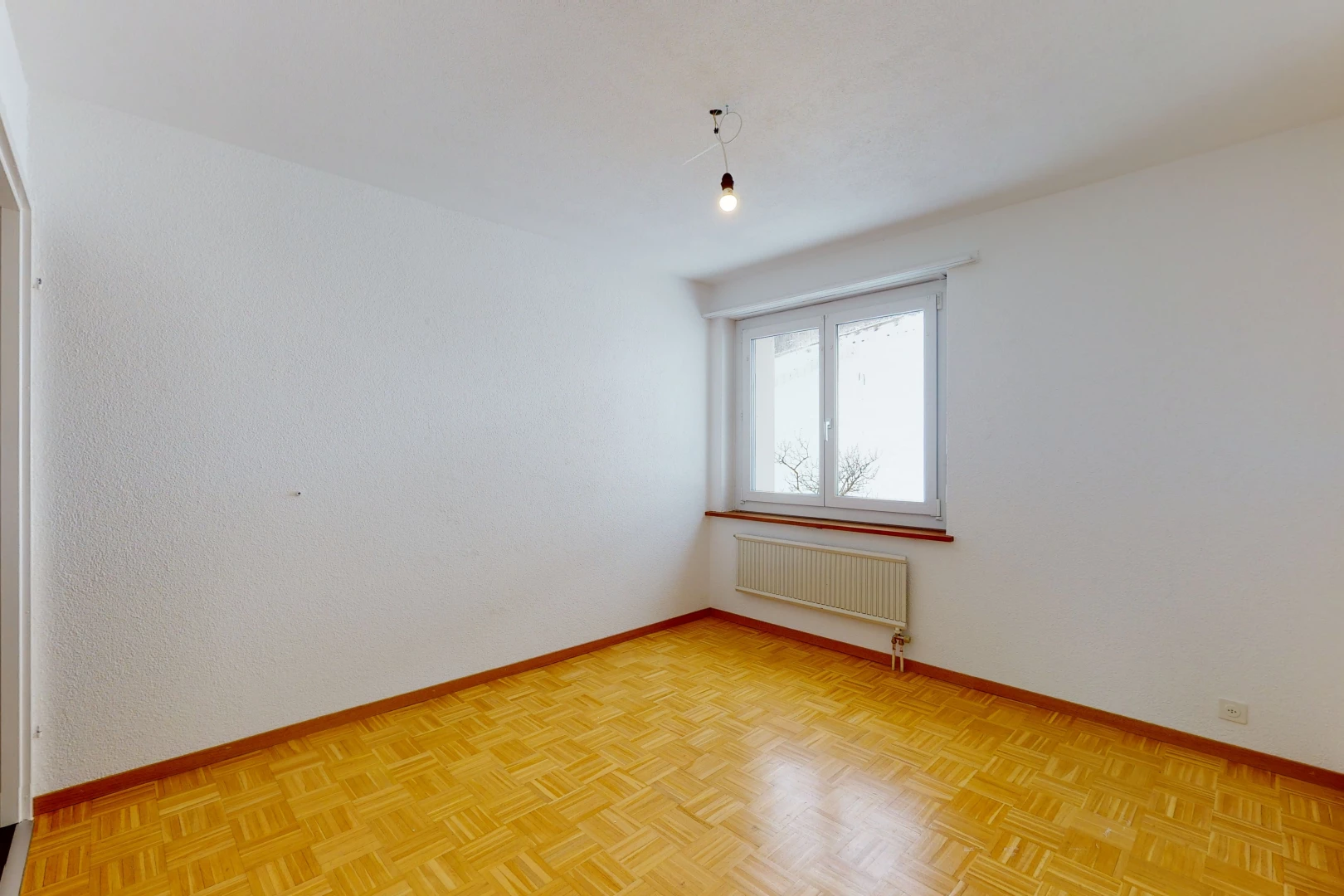 wood floored empty room with natural light and radiator