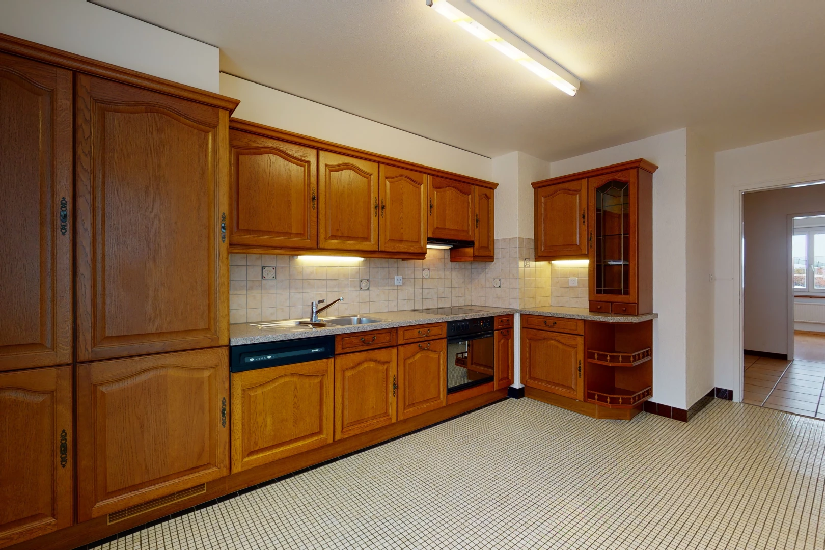 kitchen with oven, brown cabinetry, light countertops, and light tile floors