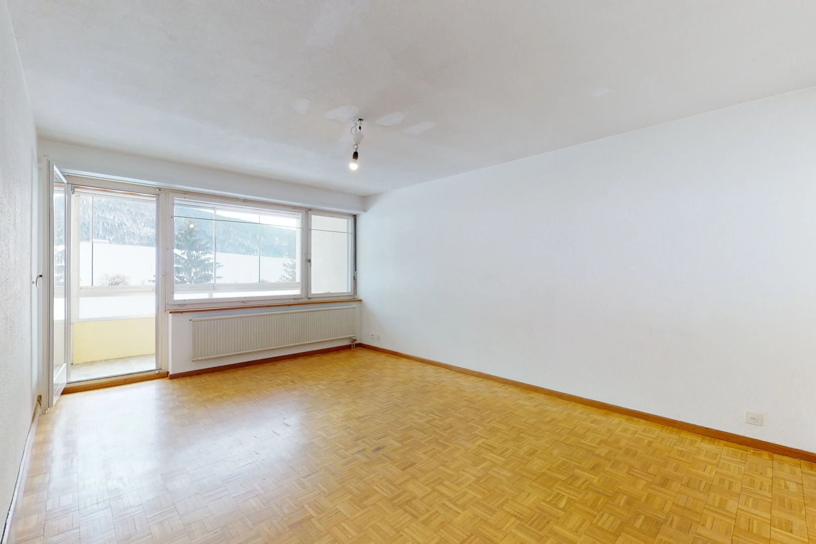 hardwood floored spare room featuring natural light and radiator