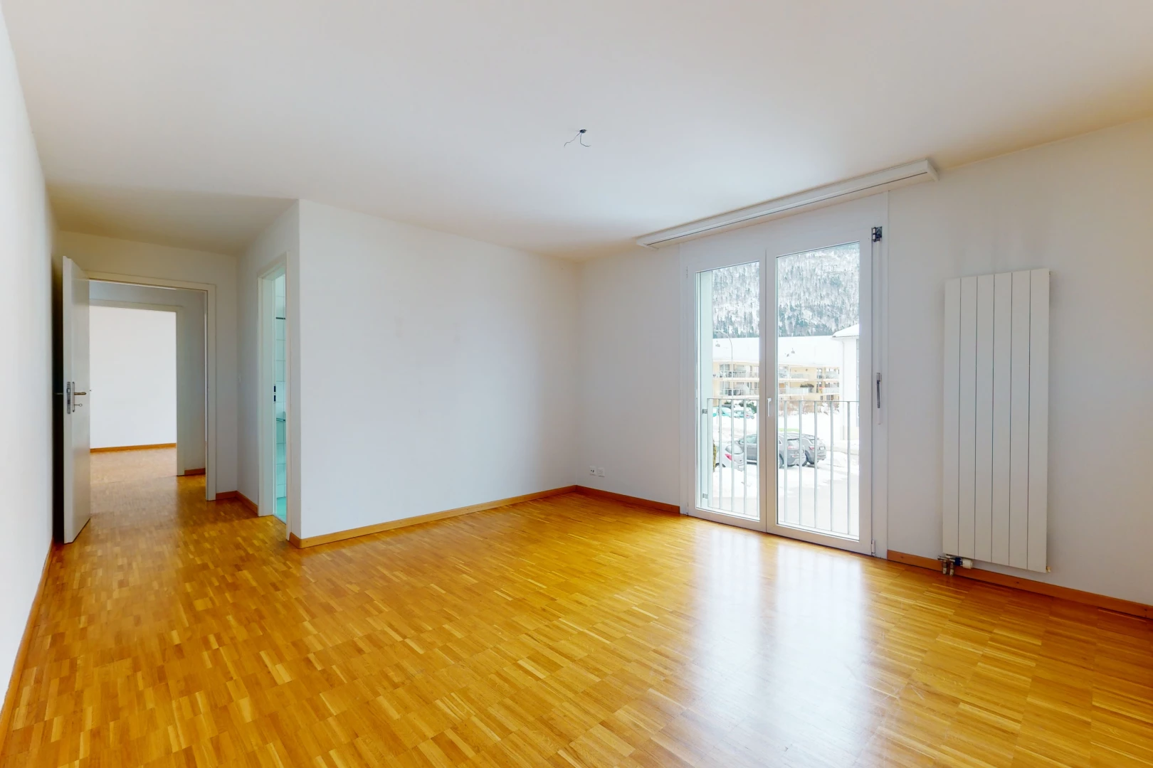 hardwood floored spare room with natural light and radiator