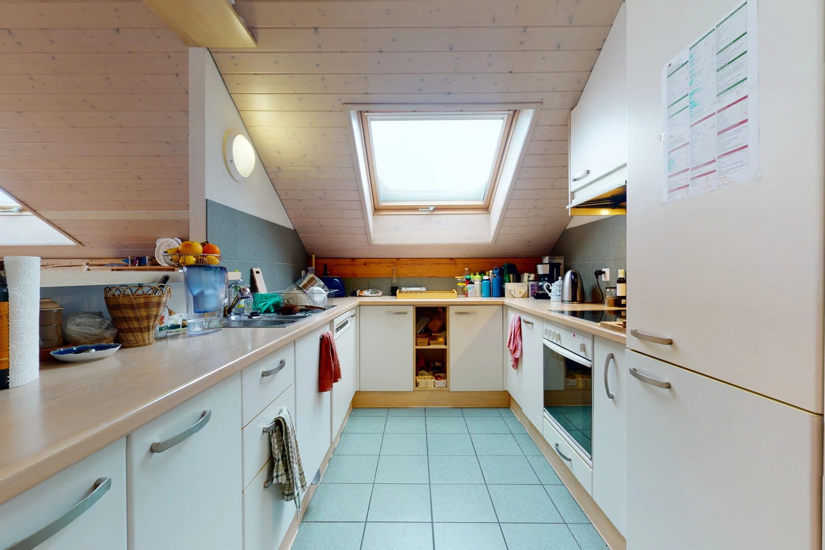 kitchen featuring skylight, oven, electric cooktop, light tile flooring, white cabinets, and light countertops