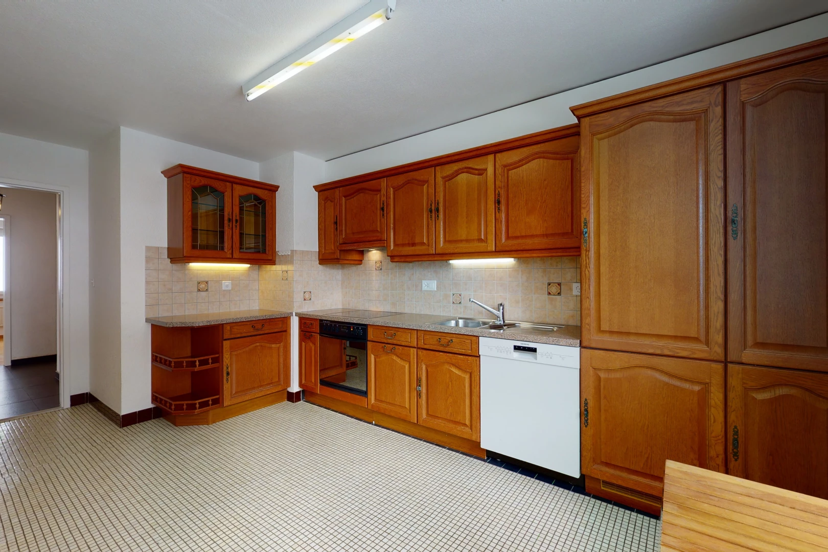 kitchen featuring dishwasher, brown cabinetry, light floors, and light countertops