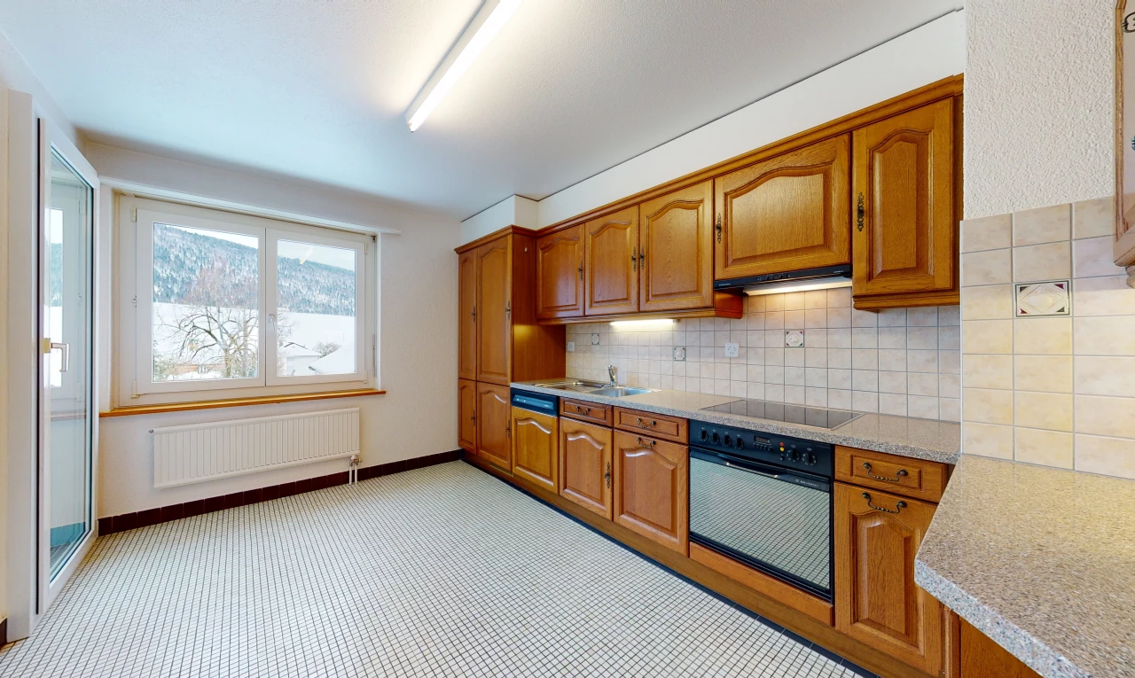 kitchen featuring natural light, radiator, oven, electric cooktop, light flooring, light countertops, and brown cabinetry