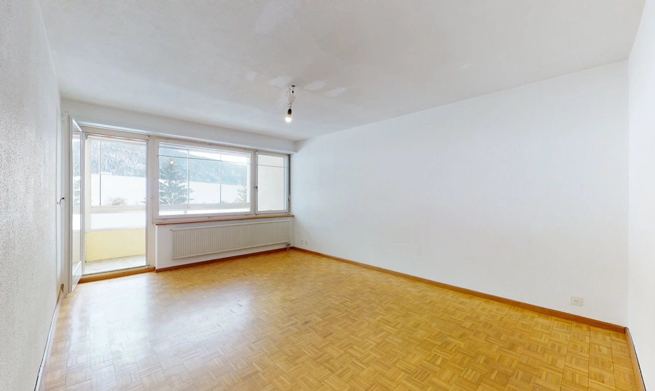 hardwood floored spare room featuring natural light and radiator