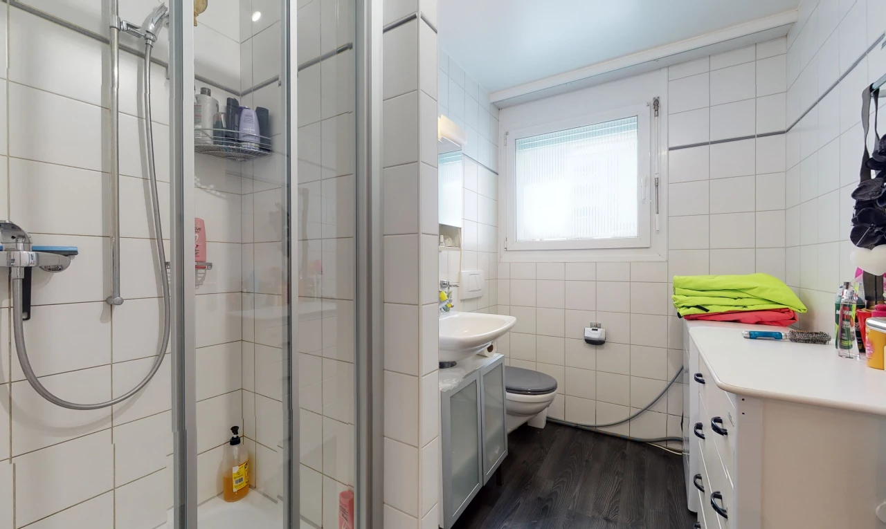 bathroom featuring natural light, wood-type flooring, toilet, dual vanities, and a shower