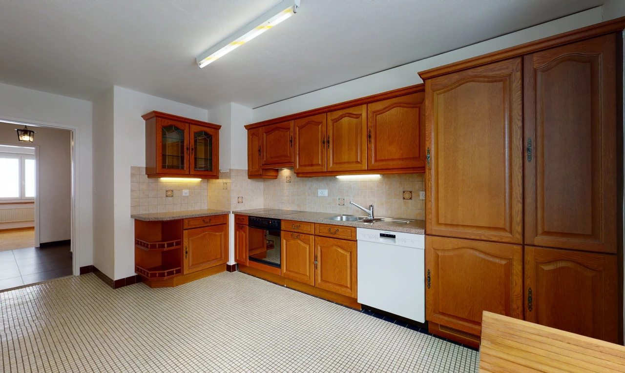 kitchen featuring dishwasher, brown cabinetry, light floors, and light countertops