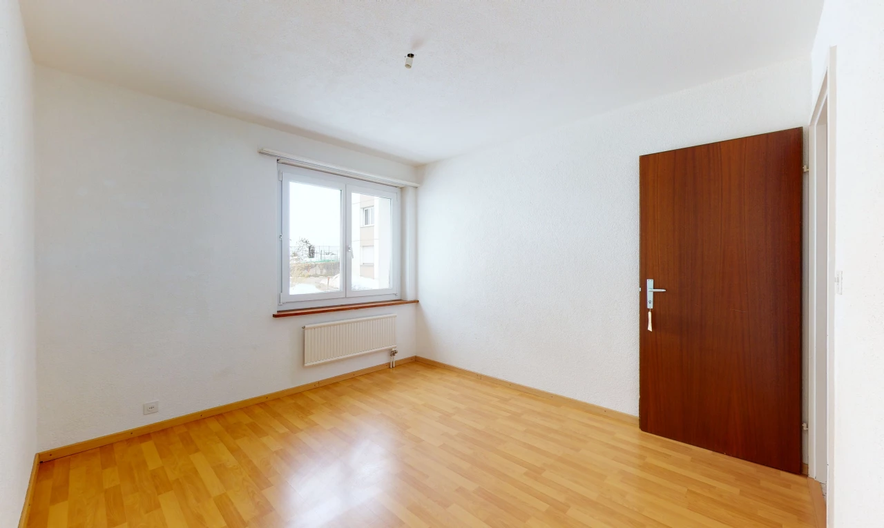 hardwood floored spare room featuring natural light and radiator