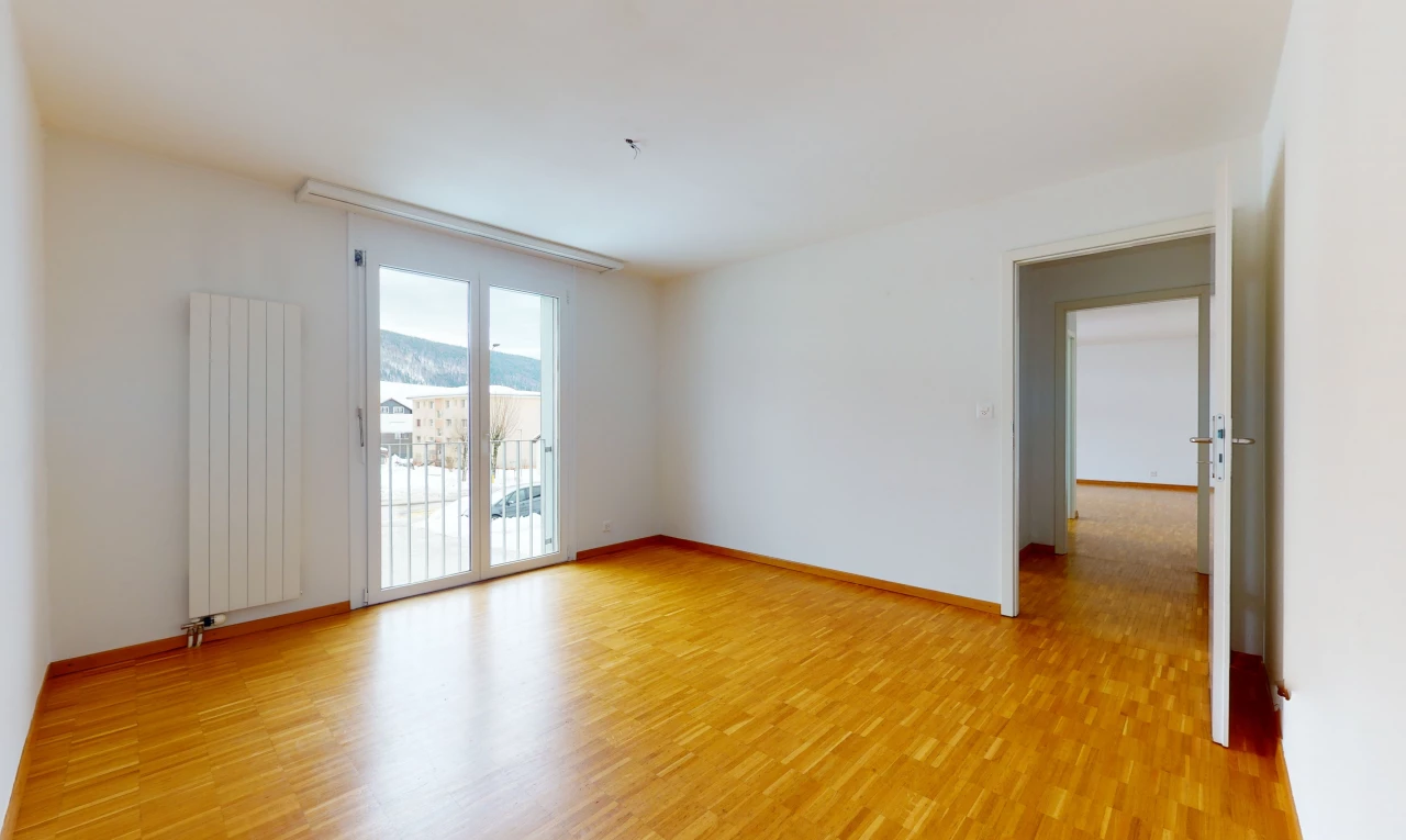 hardwood floored spare room with natural light and radiator