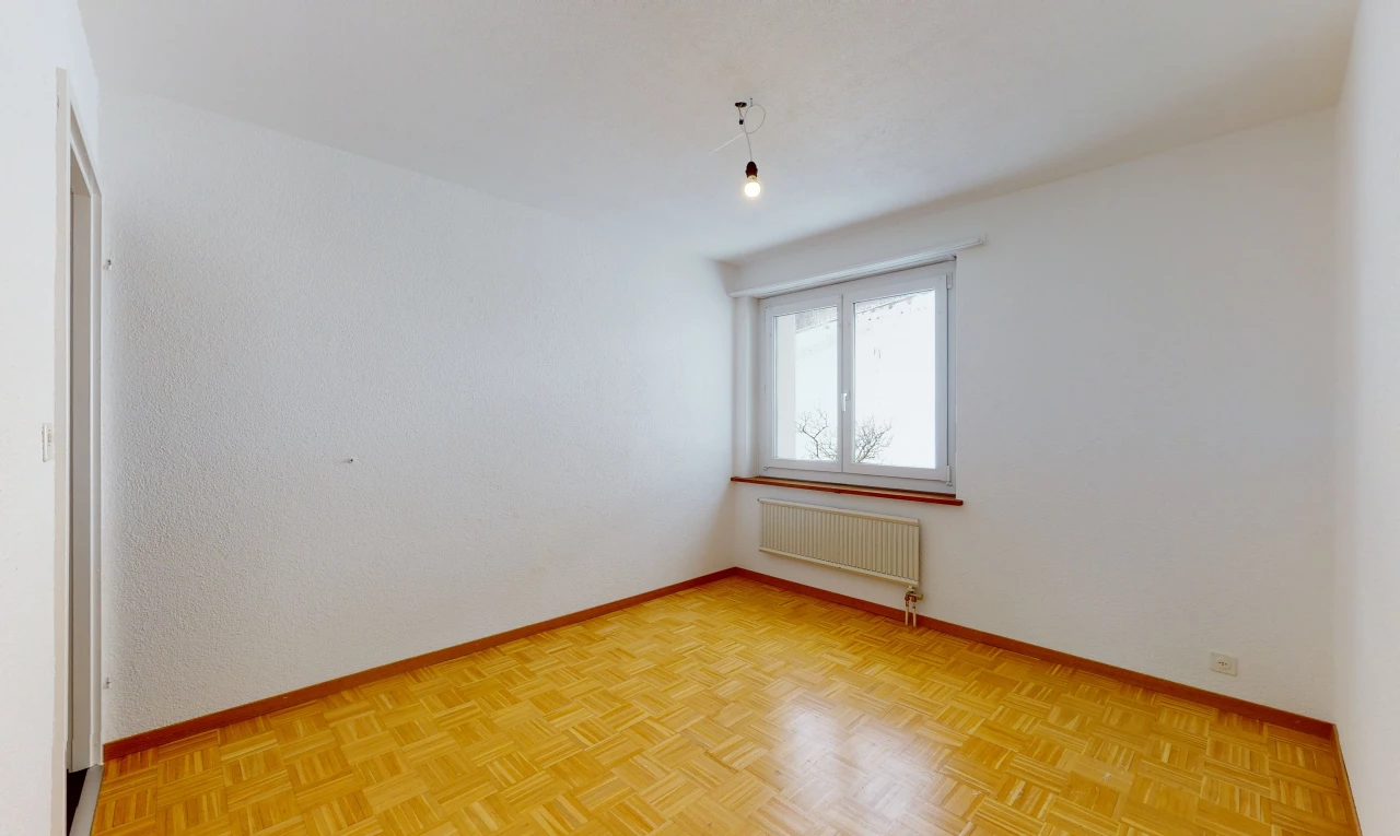 wood floored empty room with natural light and radiator