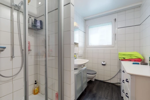bathroom featuring natural light, wood-type flooring, toilet, dual vanities, and a shower