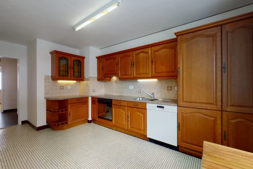 kitchen featuring dishwasher, brown cabinetry, light floors, and light countertops