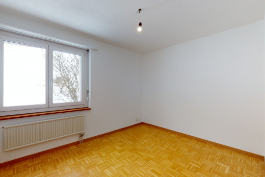 chambre vide avec lumière naturelle, parquet, et radiateur
