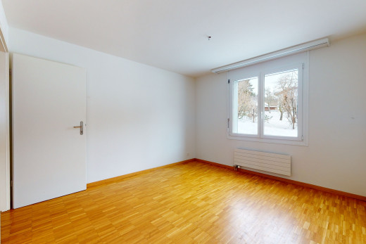 chambre vide avec parquet, lumière naturelle, et radiateur