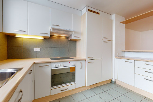 cuisine avec carrelage, cuisinière électrique, four, hotte, comptoirs claires, armoires blanches, et sol clair