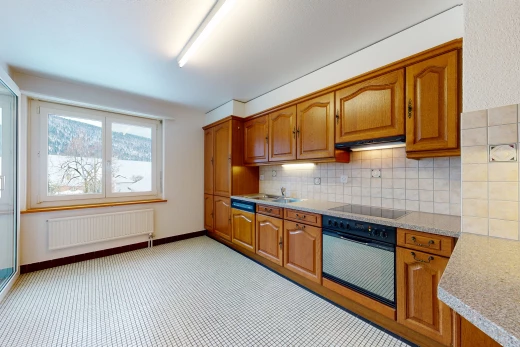 kitchen featuring natural light, radiator, oven, electric cooktop, light flooring, light countertops, and brown cabinetry