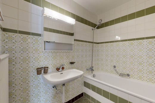 salle de bains avec radiateur, miroir, combiné baignoire-douche, et vasque