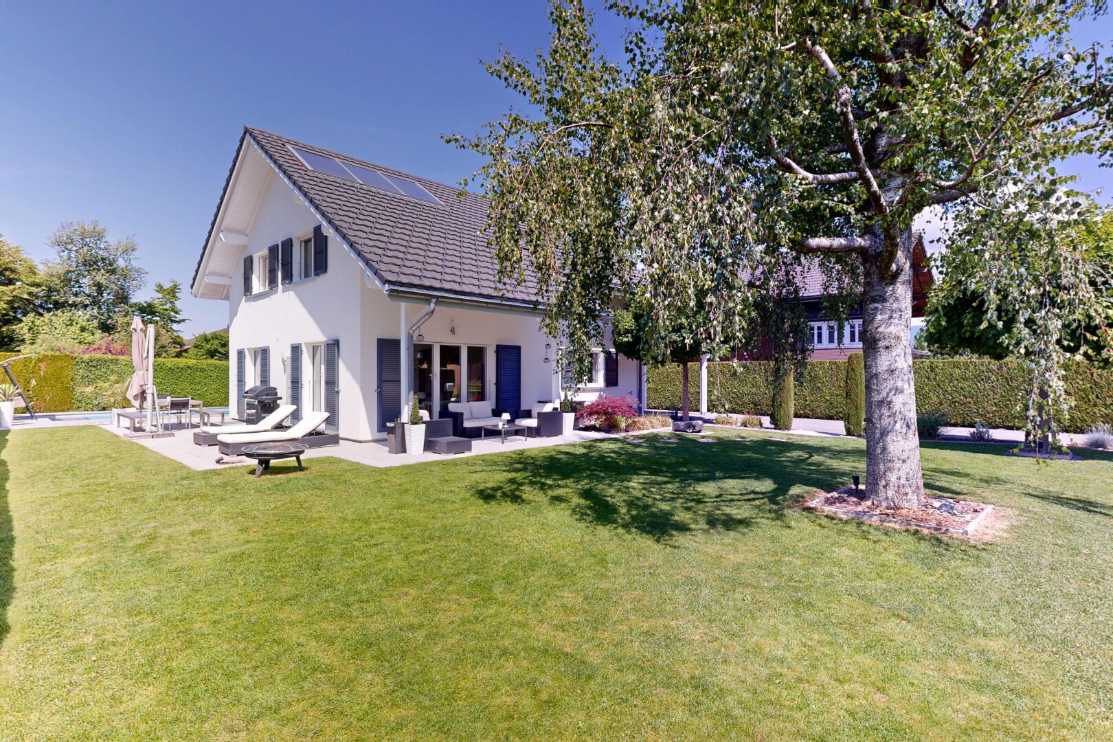 façade avec day time, pelouse, terrasse, property visible, et bardage en stuc