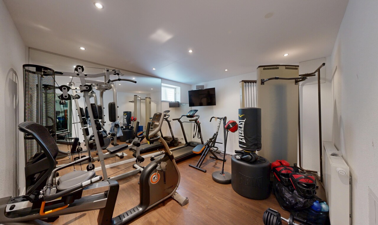 gym avec inside property, radiateur, wood finish floor, sol en finition bois, et télévision
