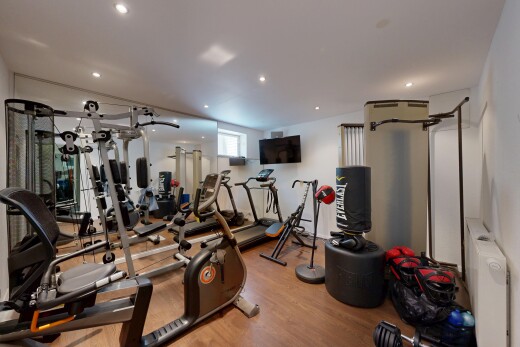 gym avec inside property, radiateur, wood finish floor, sol en finition bois, et télévision
