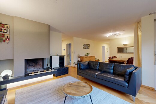 living room featuring a fireplace with raised hearth, light wood-style floors, and rail lighting