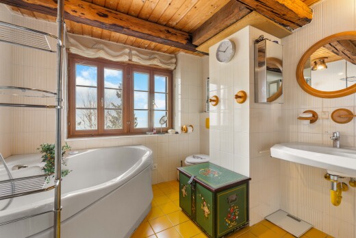 salle de bains avec mur en carrelage, tile wall, bain, miroir, et lumière naturelle