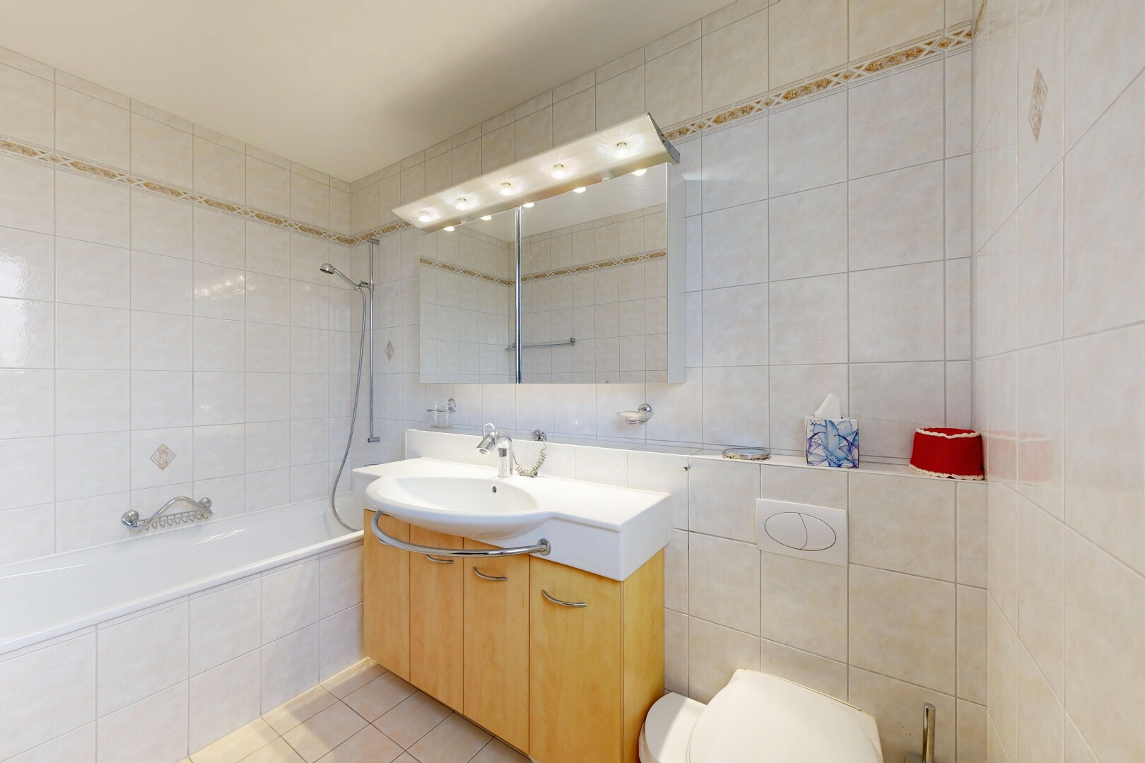 bathroom featuring tile walls, tiled shower / bath, vanity, and light tile patterned floors