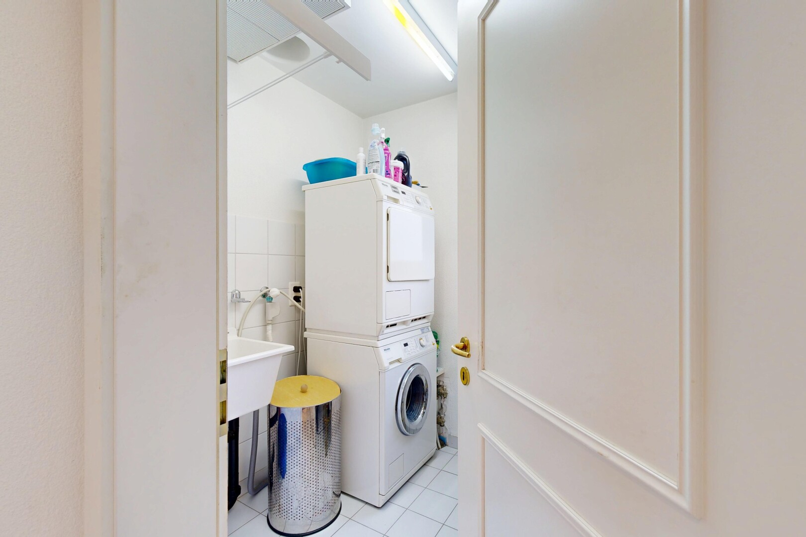 laundry room with light tile patterned flooring, stacked washer / dryer, and tile walls