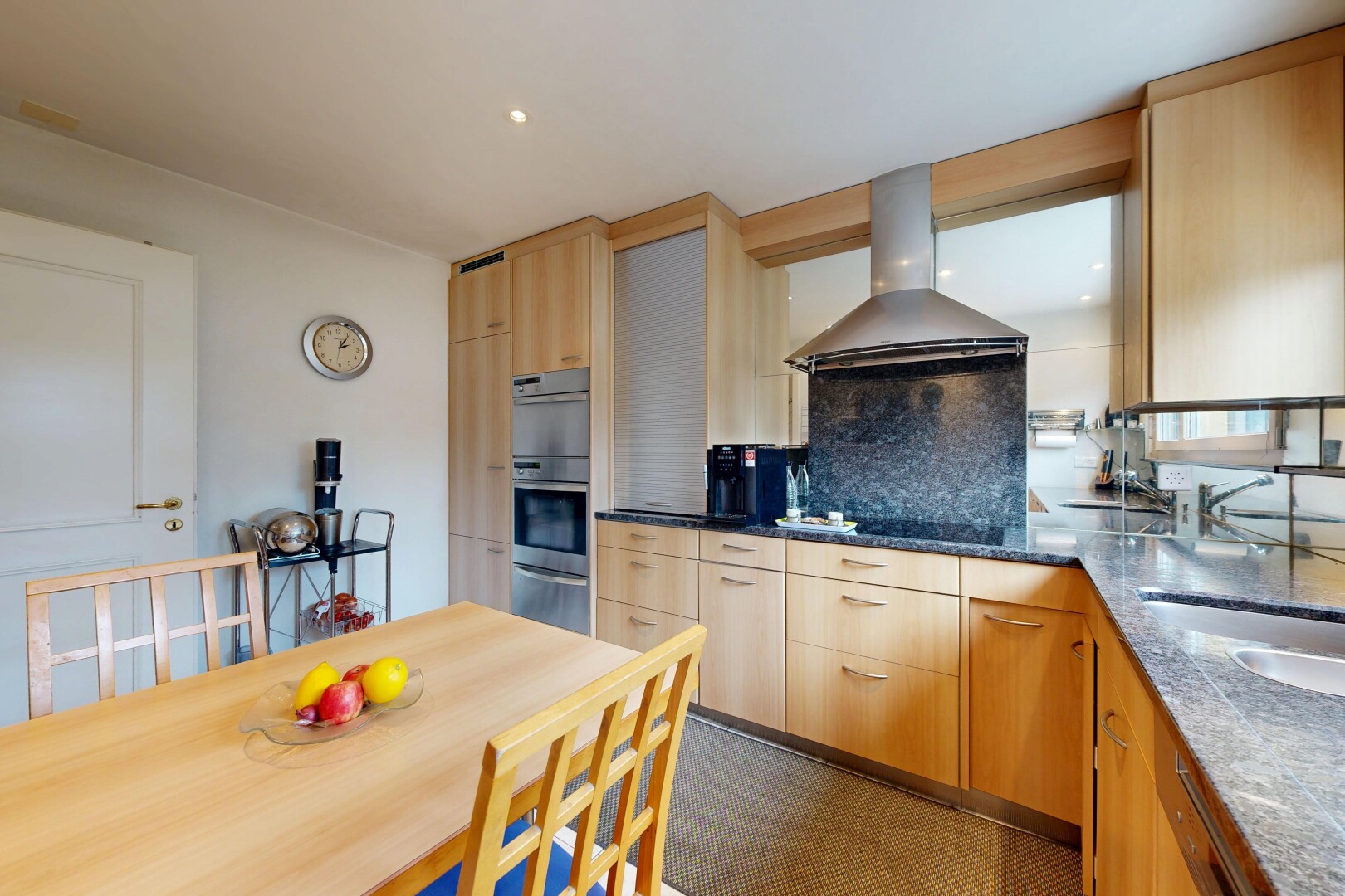 kitchen with light wood finish cabinetry, range hood, backsplash, dark stone countertops, and recessed lighting