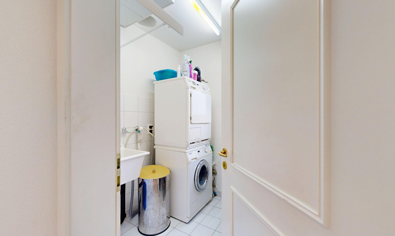laundry room with light tile patterned flooring, stacked washer / dryer, and tile walls