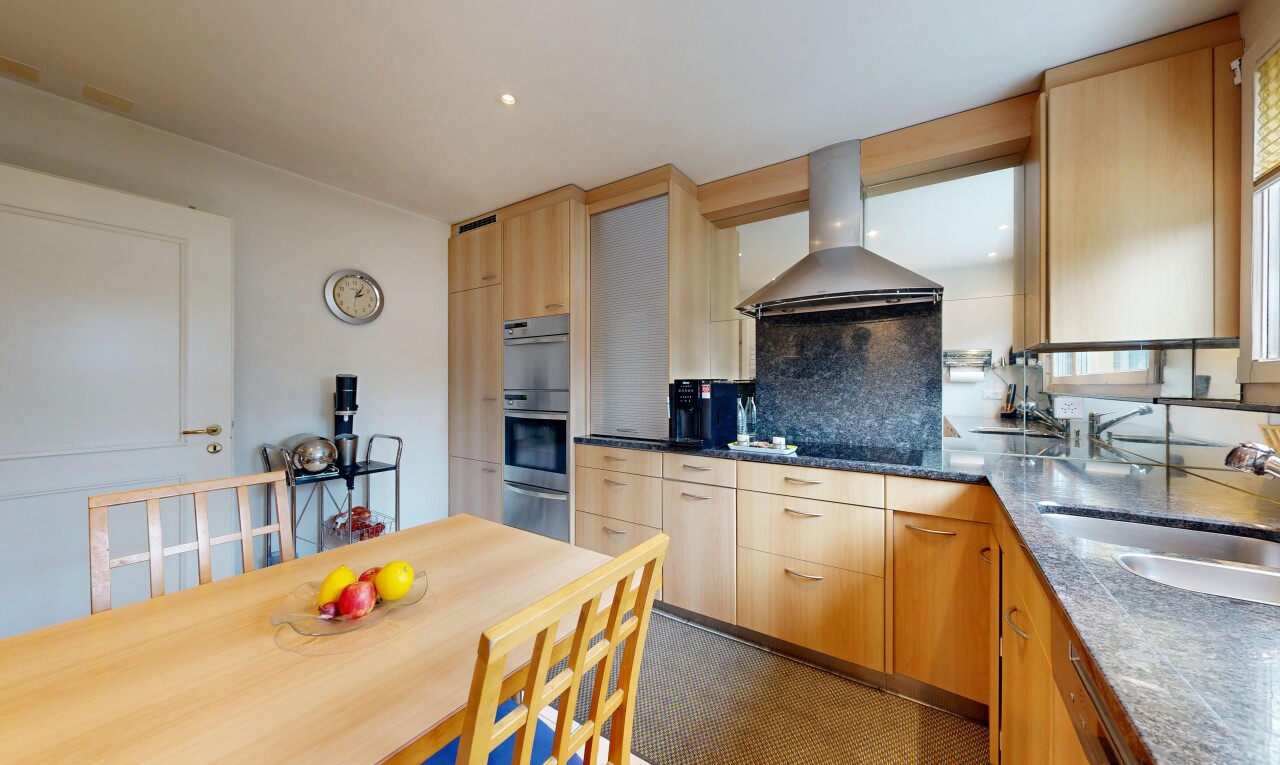 kitchen with light wood finish cabinetry, range hood, backsplash, dark stone countertops, and recessed lighting