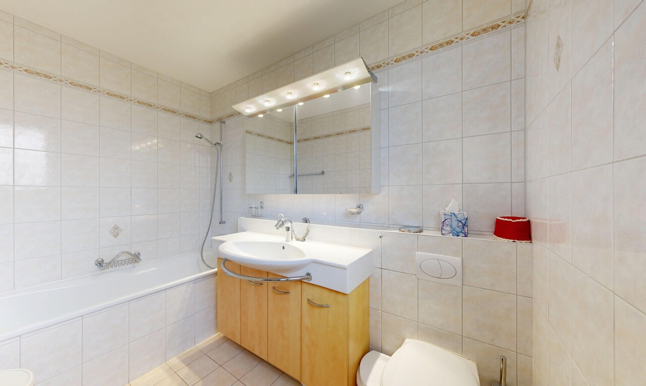 bathroom featuring tile walls, tiled shower / bath, vanity, and light tile patterned floors
