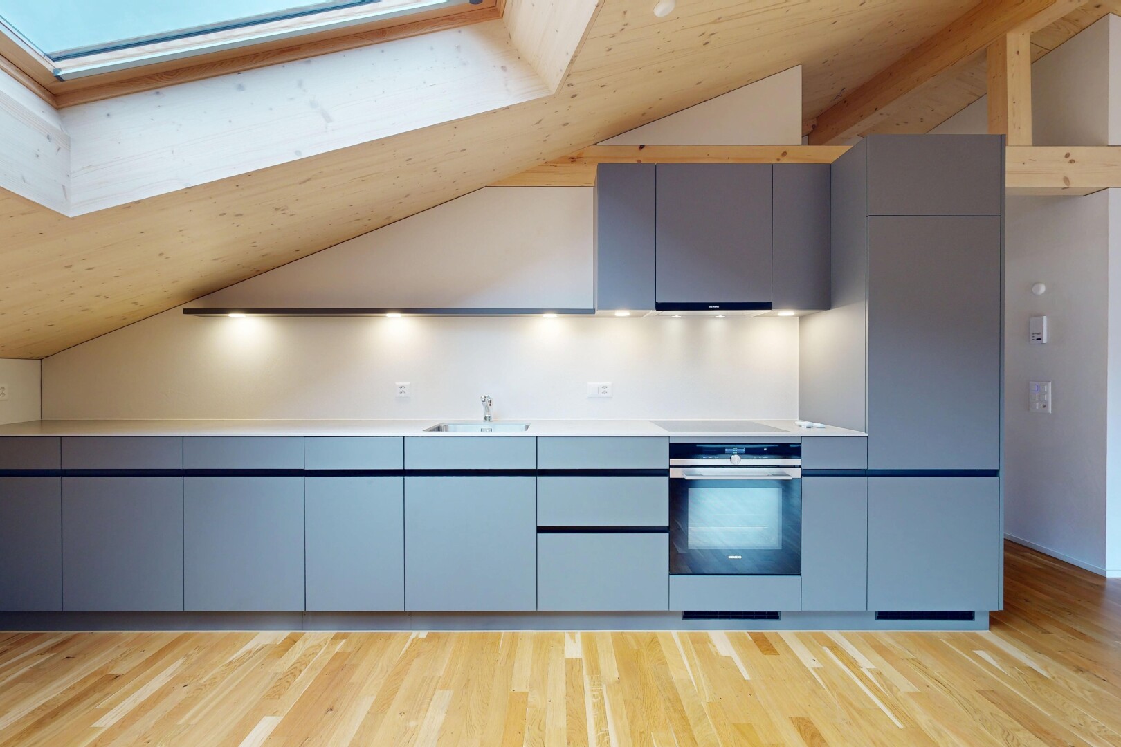 cuisine avec armoires à panneau plat, vaulted ceiling, plafond voûté, wood finish floor, et sol en finition bois