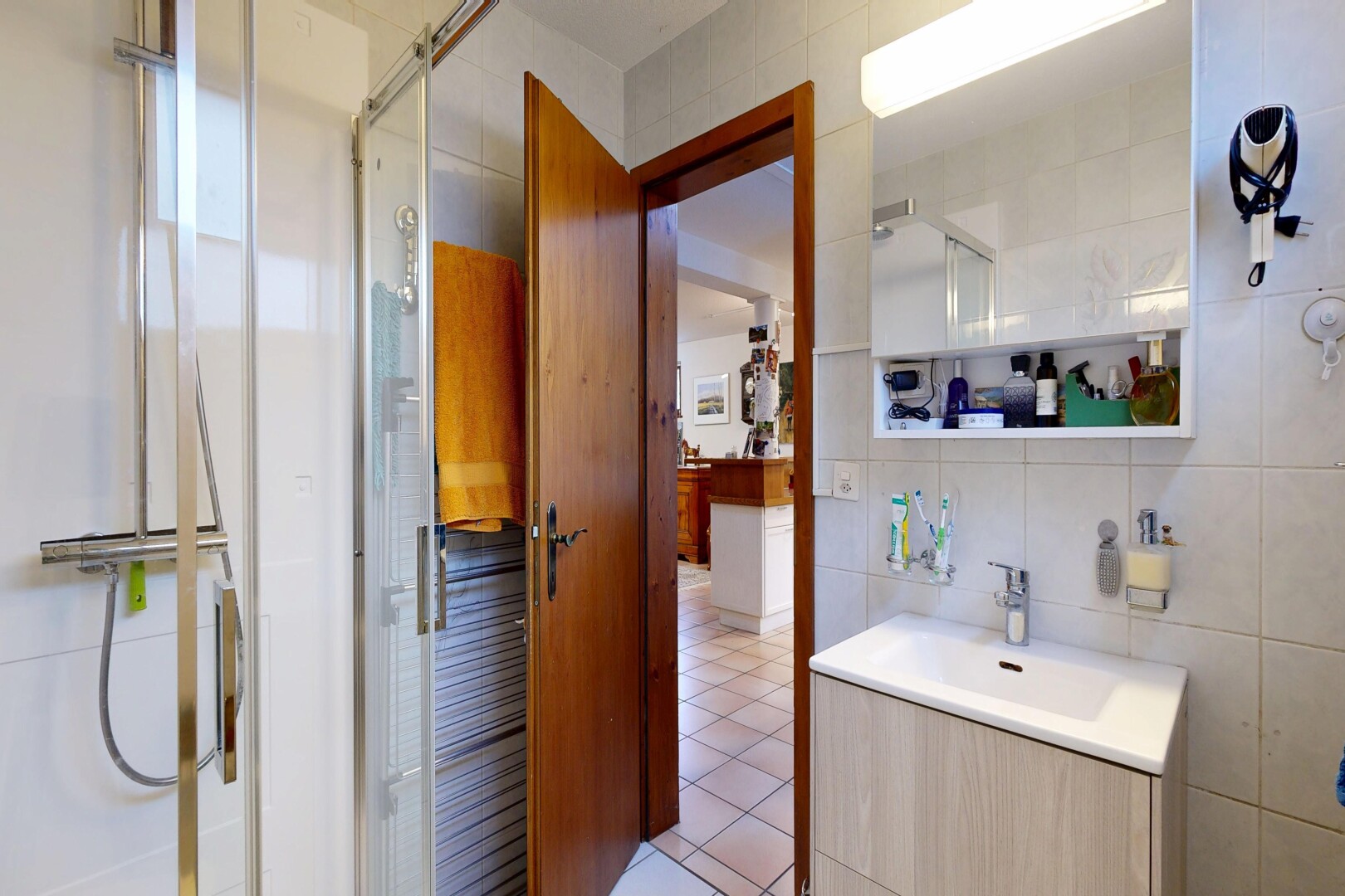 salle de bains avec tile wall, mur en carrelage, douche, miroir, et lavabo (ou coiffeuse selon le contexte)