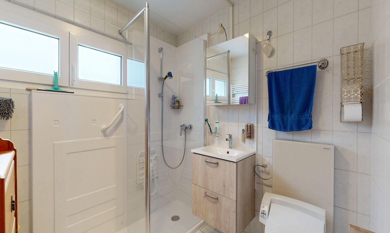 salle de bains avec lavabo (ou coiffeuse selon le contexte), salle de bain complète, miroir, douche, et tile wall