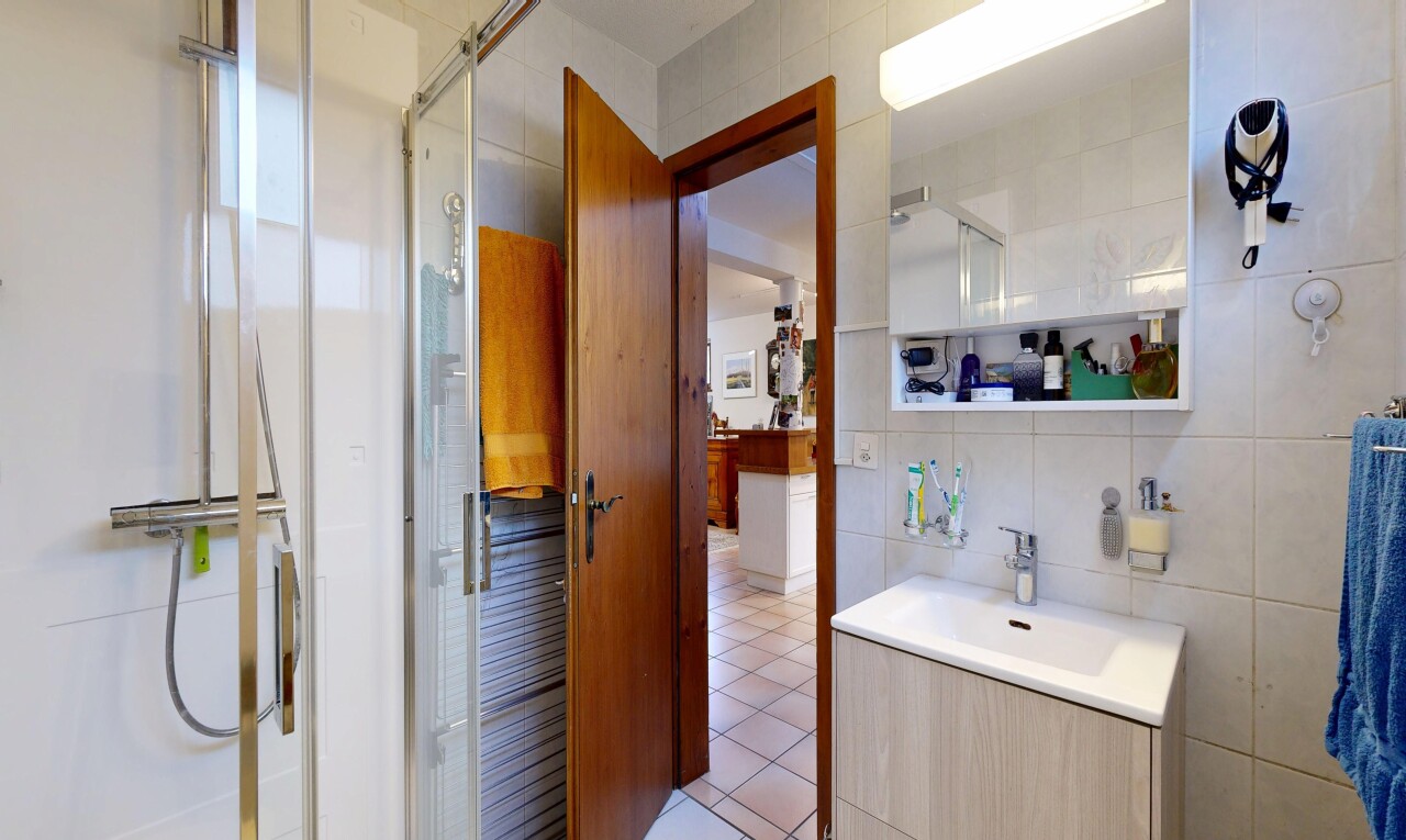 salle de bains avec tile wall, mur en carrelage, douche, miroir, et lavabo (ou coiffeuse selon le contexte)