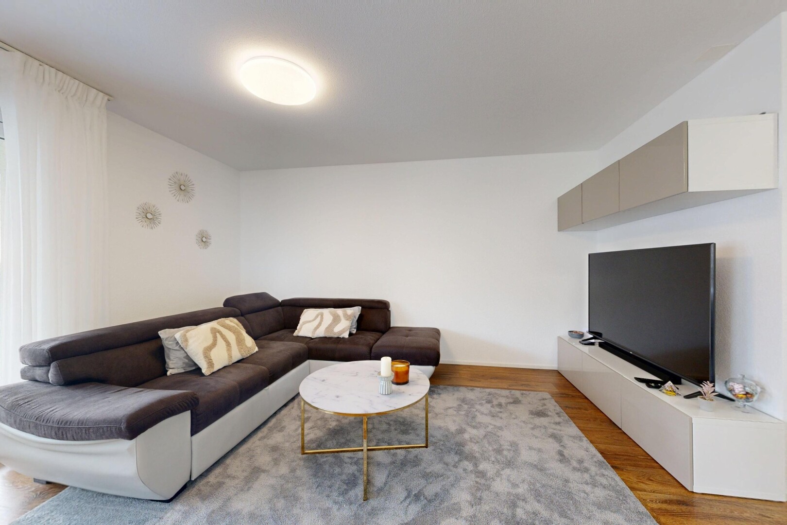 salon avec télévision, drywall, cloison sèche, wood finish floor, et sol en finition bois