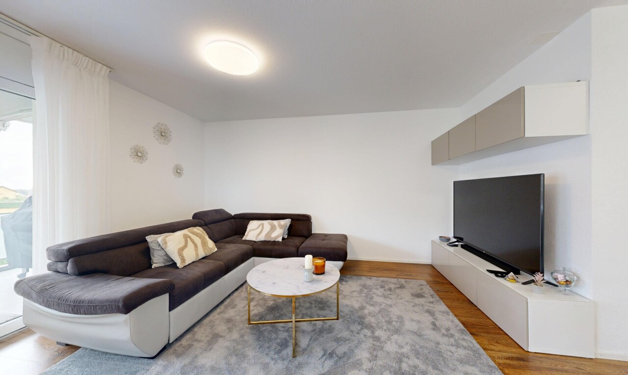 salon avec télévision, drywall, cloison sèche, wood finish floor, et sol en finition bois