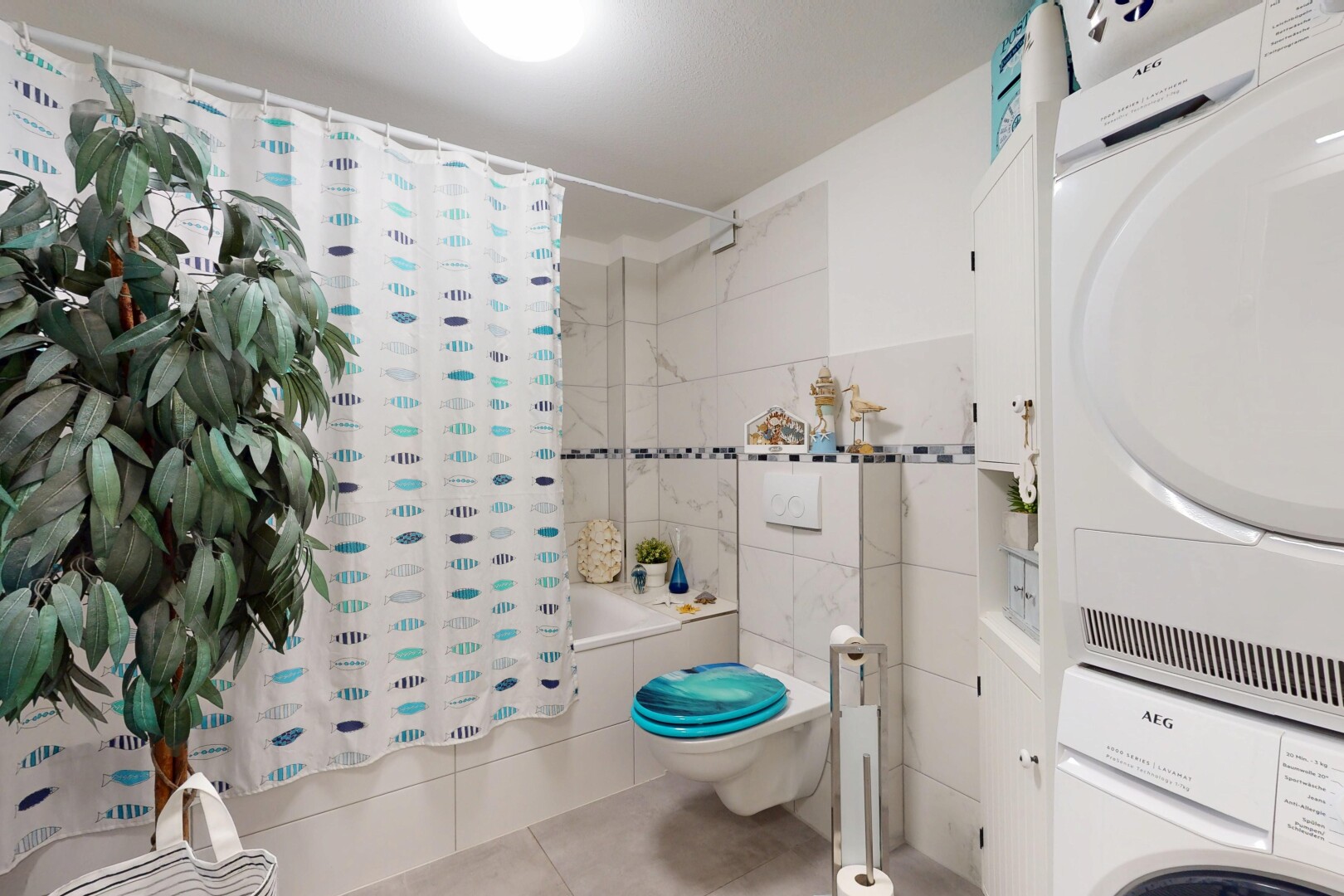 salle de bains avec lave-linge et sèche-linge superposés, douche-bain combinés, sol en carrelage, tile floor, et toilette