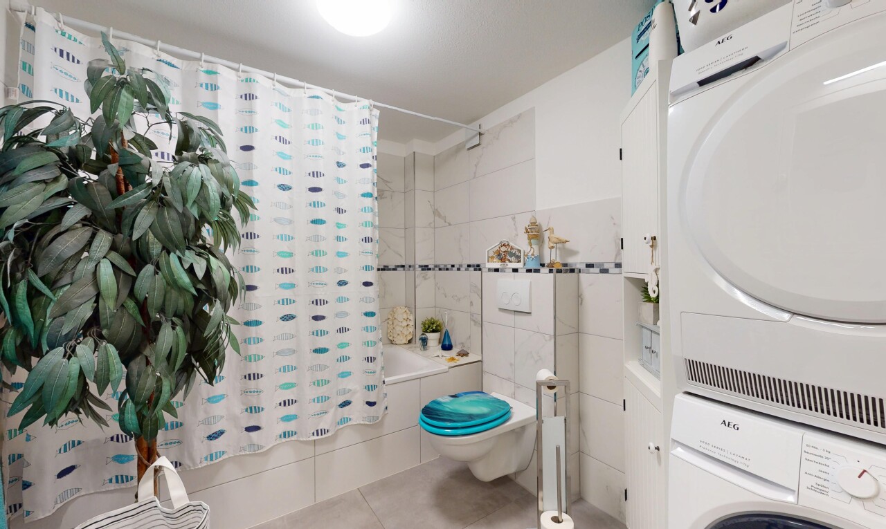 salle de bains avec lave-linge et sèche-linge superposés, douche-bain combinés, sol en carrelage, tile floor, et toilette