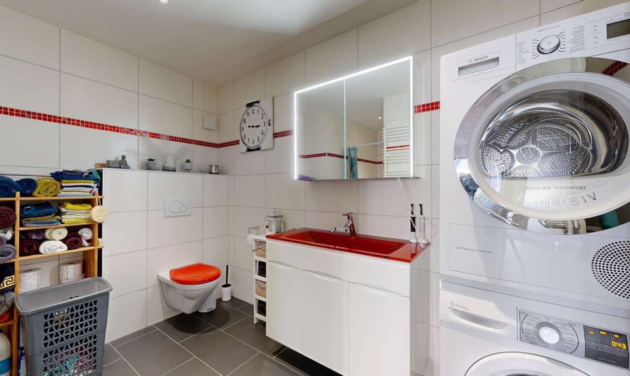 laundry room with tile walls, dark tile patterned floors, and stacked washing machine and dryer