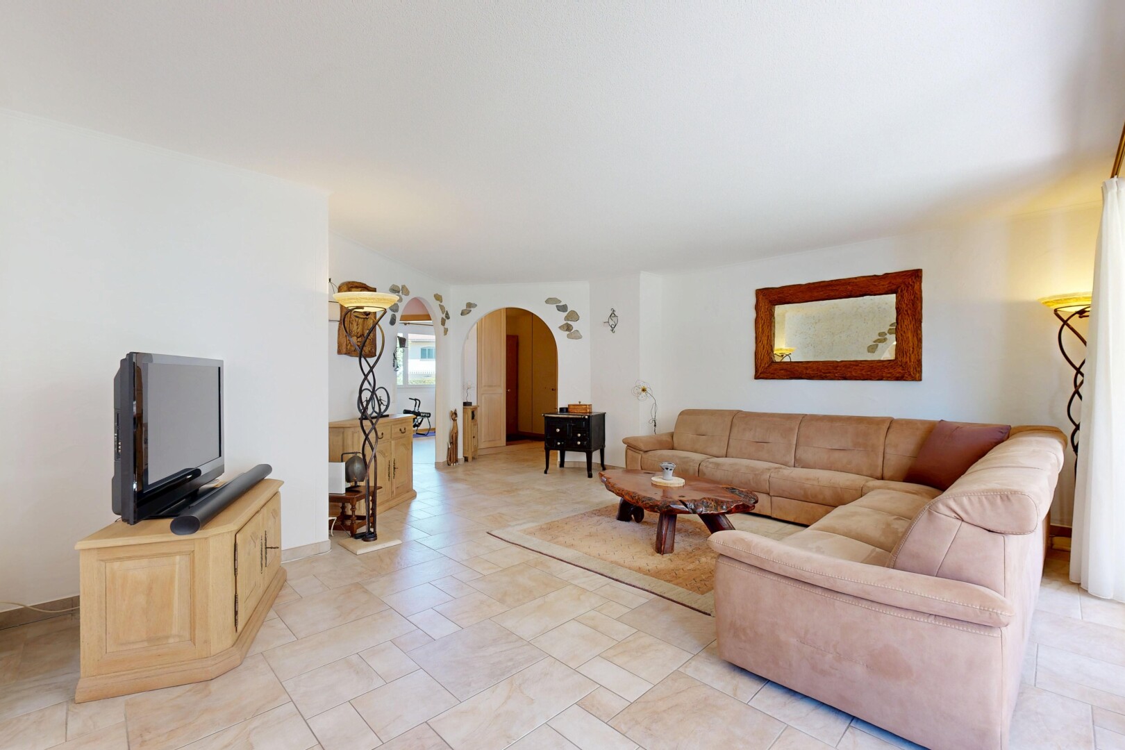 salon avec passages en arc, télévision, inside property, cloison sèche, et drywall