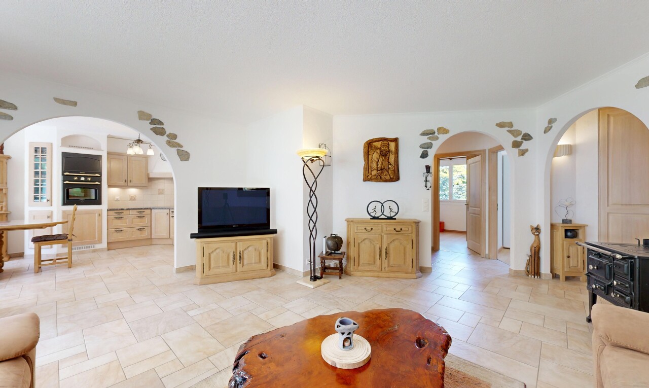 salon avec passages en arc, inside property, light floor, télévision, et natural light