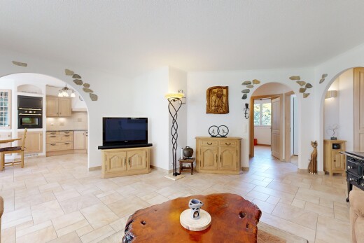salon avec passages en arc, inside property, light floor, télévision, et natural light