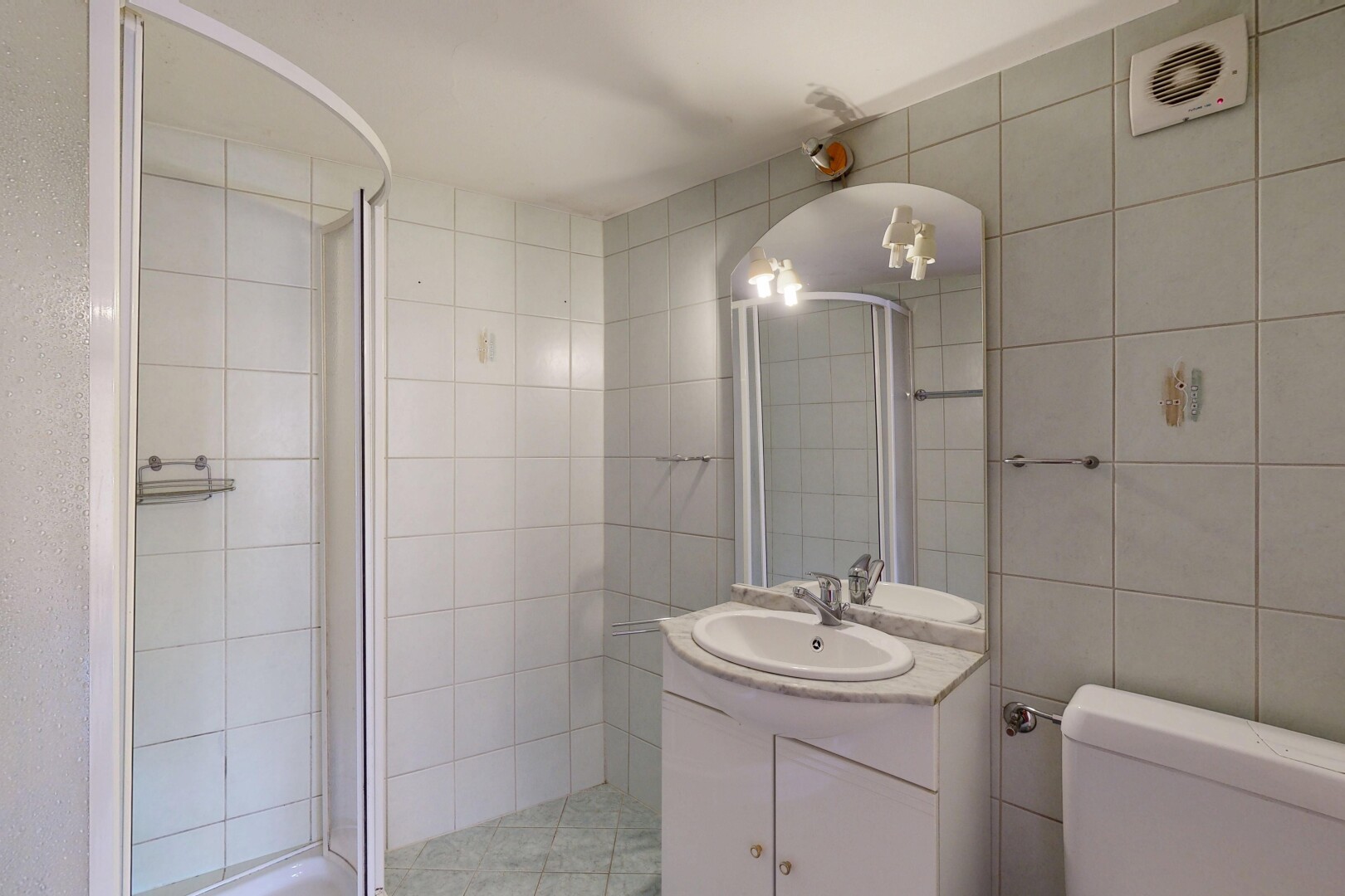 salle de bains avec tile wall, mur en carrelage, miroir, lavabo (ou coiffeuse selon le contexte), et douche
