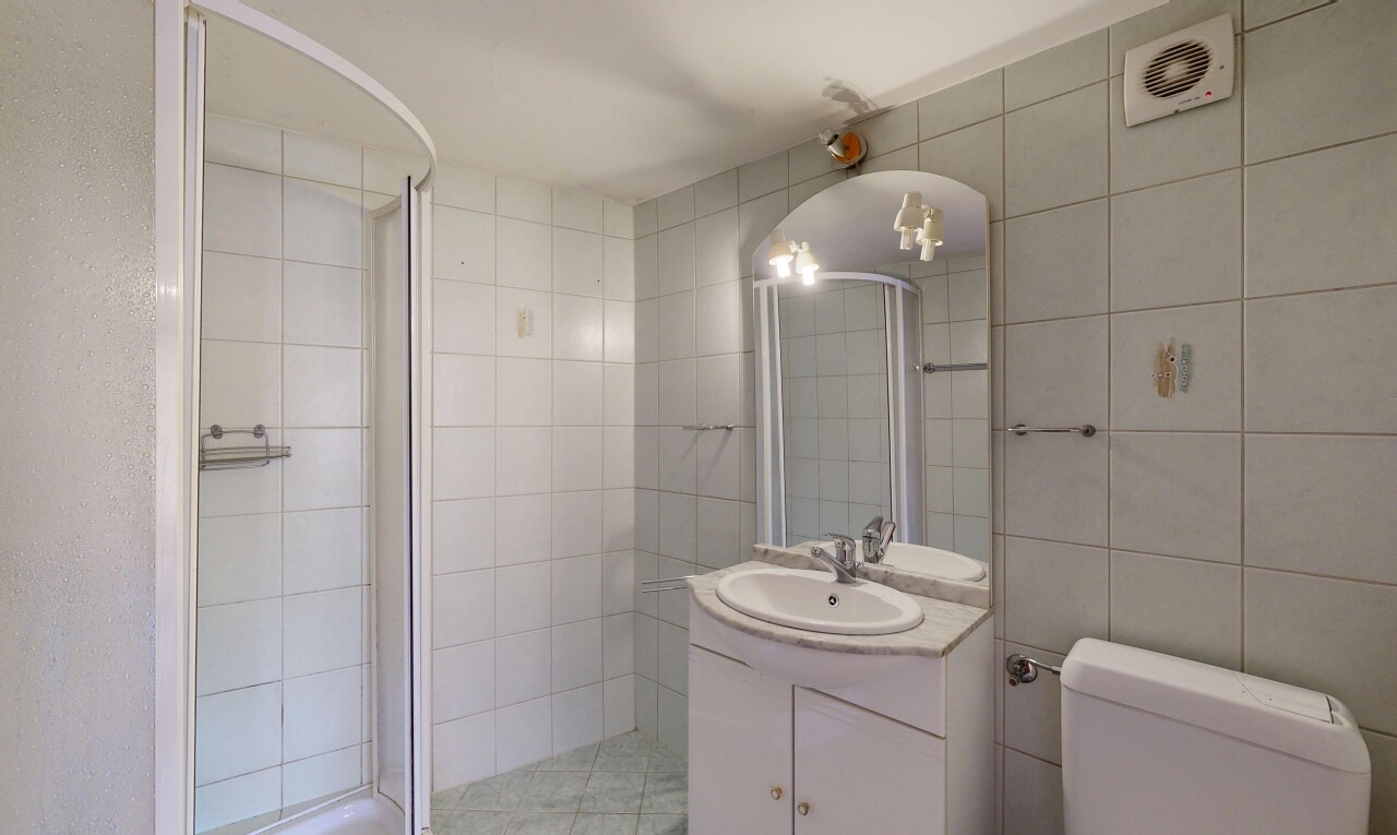 salle de bains avec tile wall, mur en carrelage, miroir, lavabo (ou coiffeuse selon le contexte), et douche